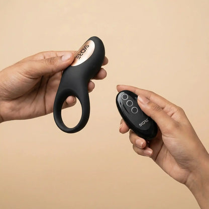Skore Buzzz vibrating ring and remote held in hands showing the ergonomic design and gold accents.
